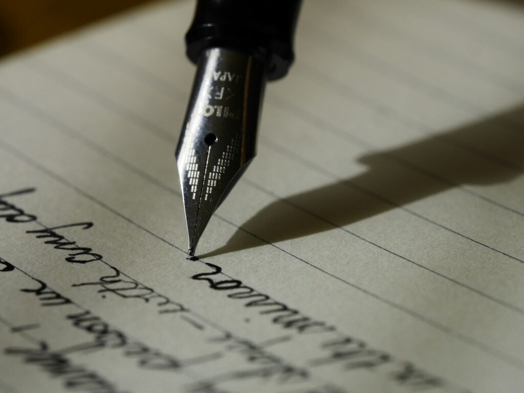 Masada açık defter ve kalemle blog yazısı planlayan kişi