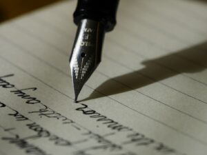 Masada açık defter ve kalemle blog yazısı planlayan kişi