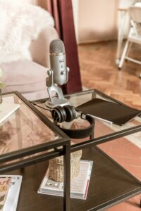 Stüdyoda cam masanın üzerinde duran podcast mikrofonu