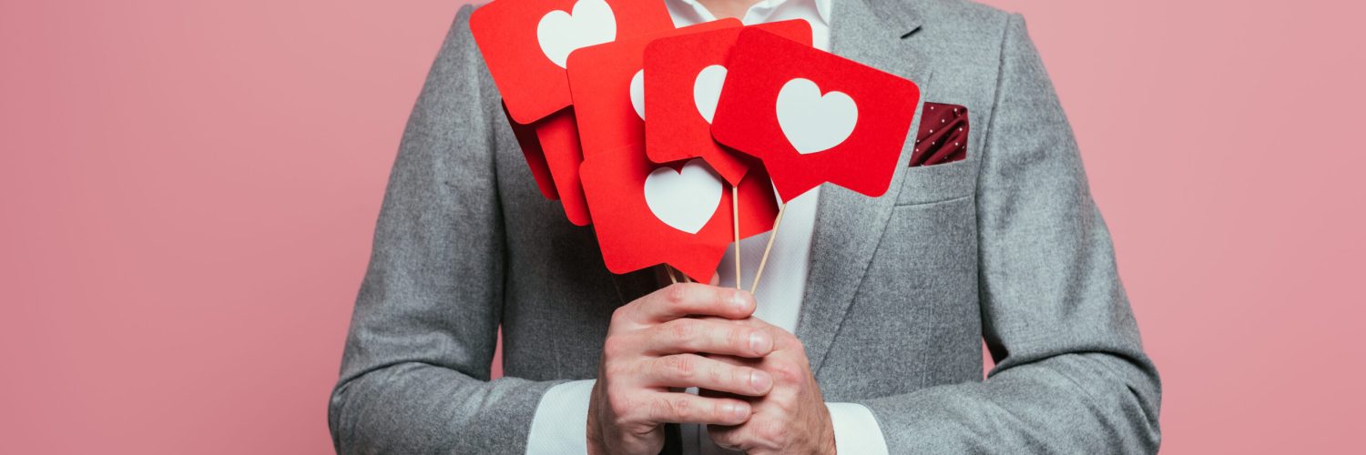 cropped view of man holding cards with hearts for valentines day, isolated on pink